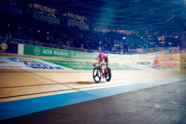 Bahnradfahrer im Rennen auf einer steilen Holzradbahn bei einem internationalen Bahnrad-Event in Berlin. 