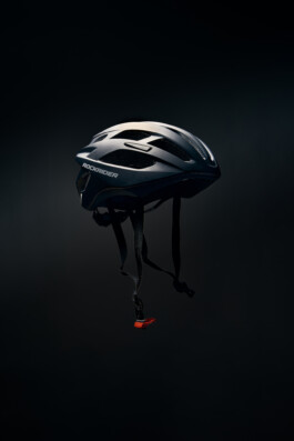 Schwarzer Fahrradhelm mit Belüftungsöffnungen, freigestellt vor dunklem Hintergrund. 