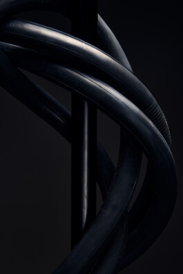 Schwarzer Fahrradhelm mit Belüftungsöffnungen, freigestellt vor dunklem Hintergrund. 