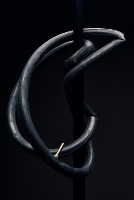 Schwarzer Fahrradhelm mit Belüftungsöffnungen, freigestellt vor dunklem Hintergrund. 