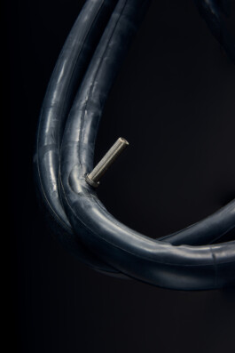 Schwarzer Fahrradhelm mit Belüftungsöffnungen, freigestellt vor dunklem Hintergrund. 