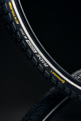 Schwarzer Fahrradhelm mit Belüftungsöffnungen, freigestellt vor dunklem Hintergrund. 