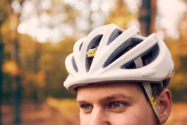 Rennradfahrer fährt auf einer Straße durch den Grunewald – dynamische Szene mit herbstlicher Natur. 
