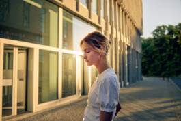 Junge Frau fährt mit einem minimalistischen City-Bike durch eine moderne Berliner Straße. 
