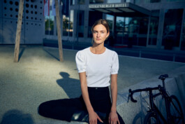 Junge Frau fährt mit einem minimalistischen City-Bike durch eine moderne Berliner Straße. 