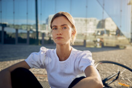 Junge Frau fährt mit einem minimalistischen City-Bike durch eine moderne Berliner Straße. 