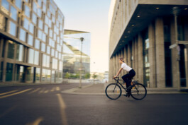 Junge Frau fährt mit einem minimalistischen City-Bike durch eine moderne Berliner Straße. 