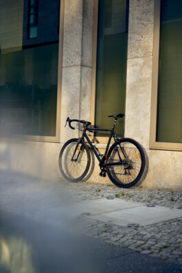 Junge Frau fährt mit einem minimalistischen City-Bike durch eine moderne Berliner Straße. 