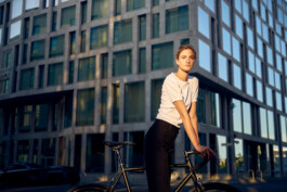 Junge Frau fährt mit einem minimalistischen City-Bike durch eine moderne Berliner Straße. 